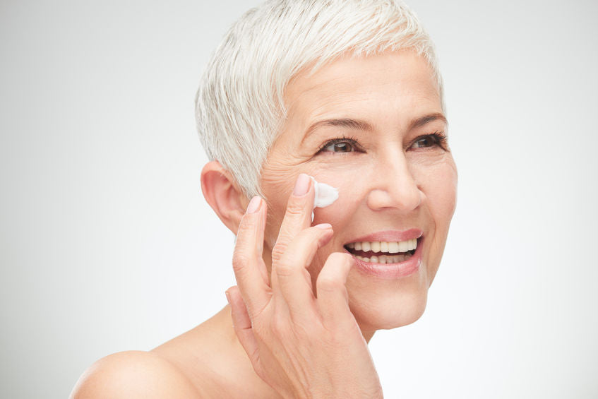 Mature women applying cream for  beautiful skin